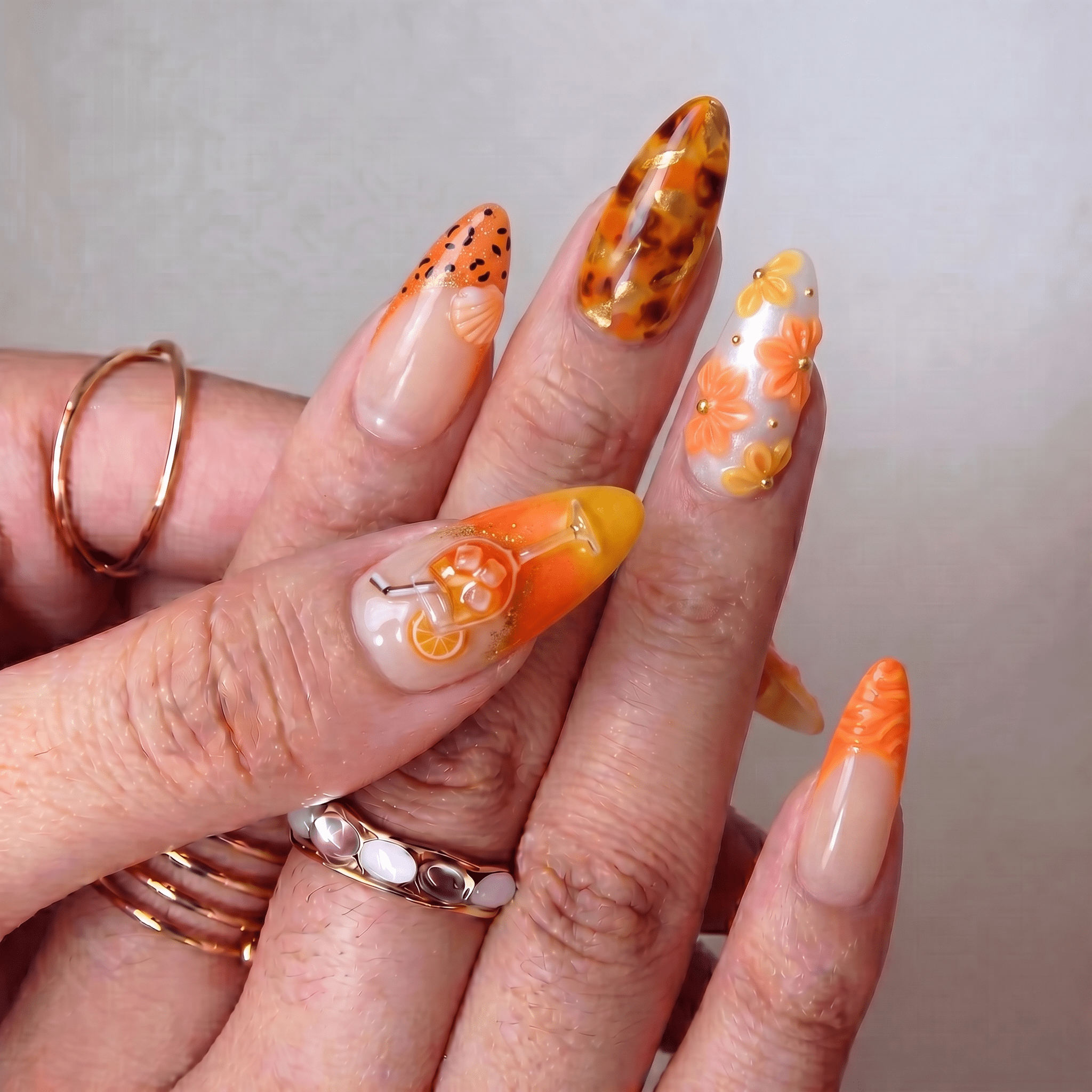 Aperol Spritz press-on nails worn on hand – almond shape by Handora