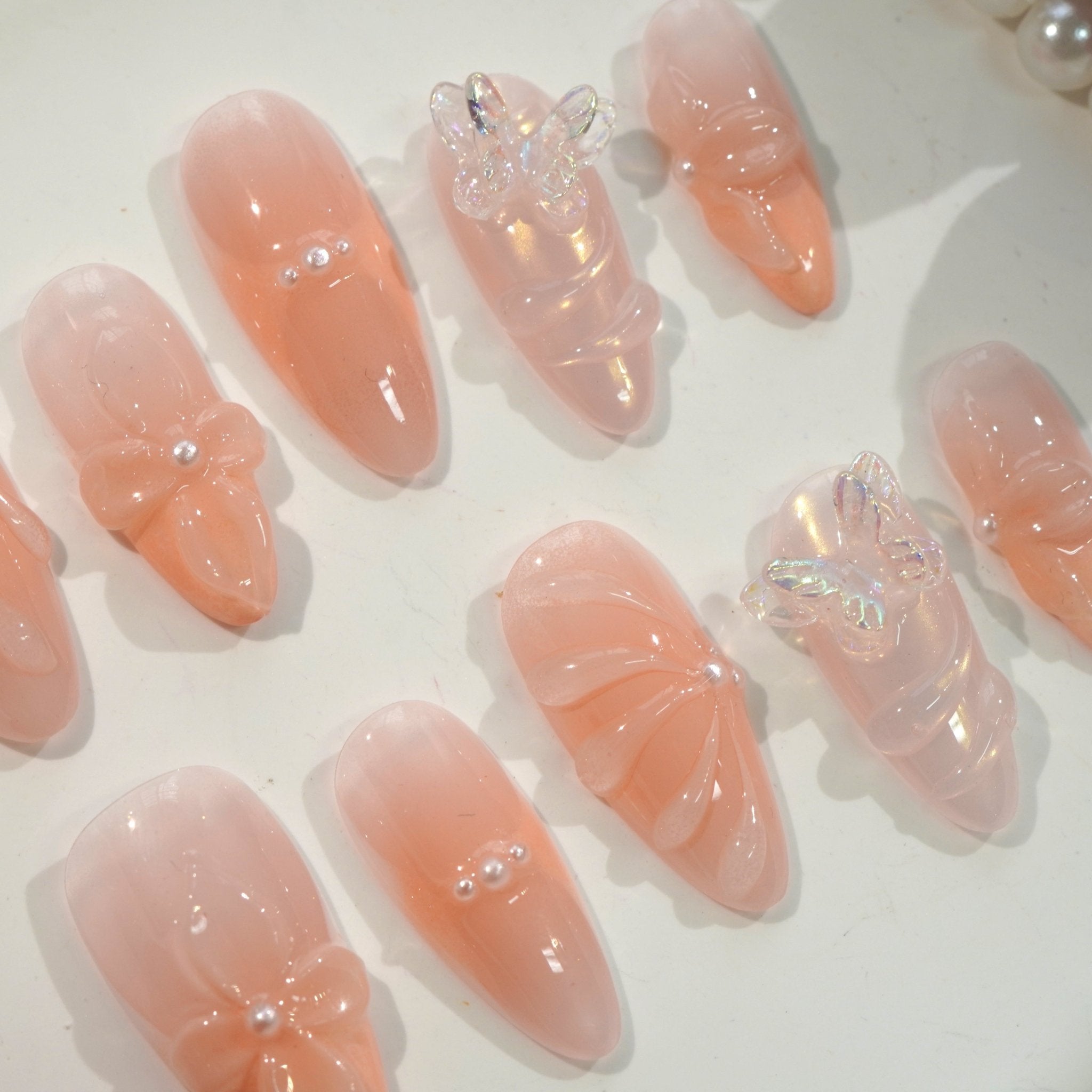 Blossom Coquette press-on nails worn on hand – almond shape by Handora