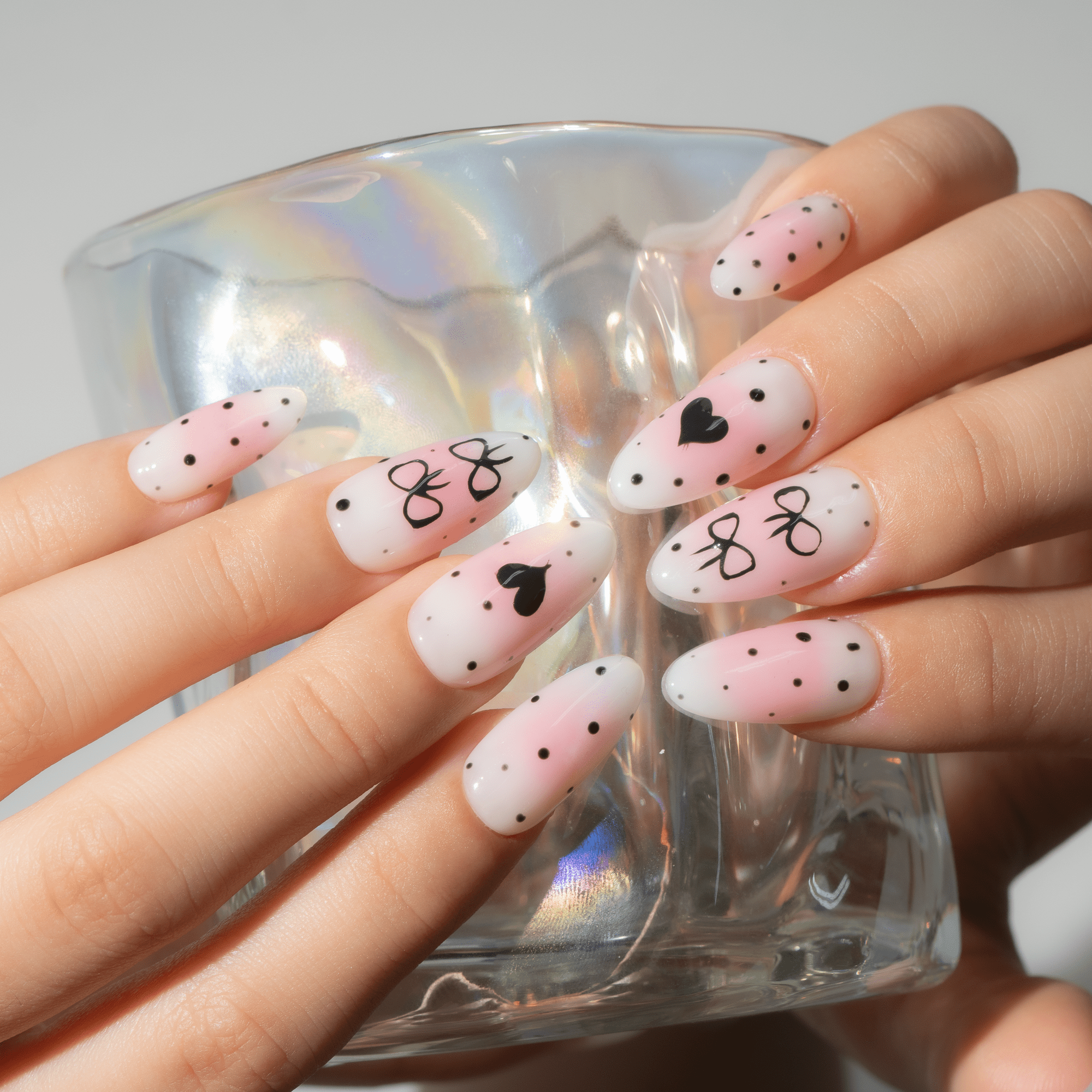 Bow Heart press-on nails worn on hand – almond shape by Handora