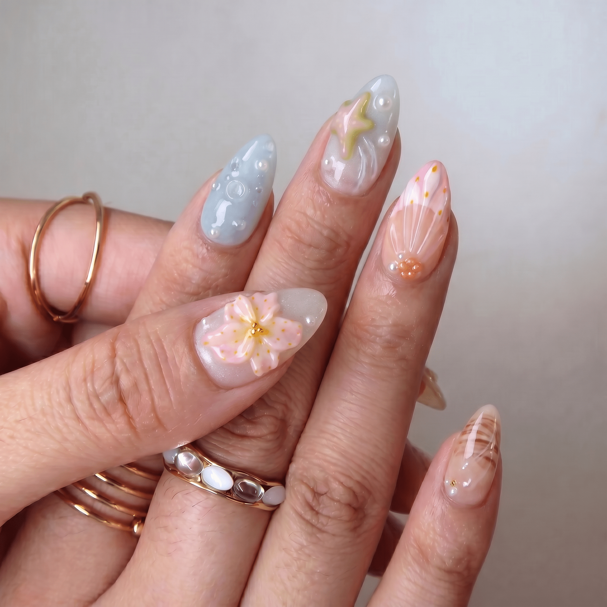 Coastal Wonders press-on nails worn on hand – almond shape by Handora