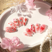Coquette Kiss press-on nails worn on hand – almond shape by Handora