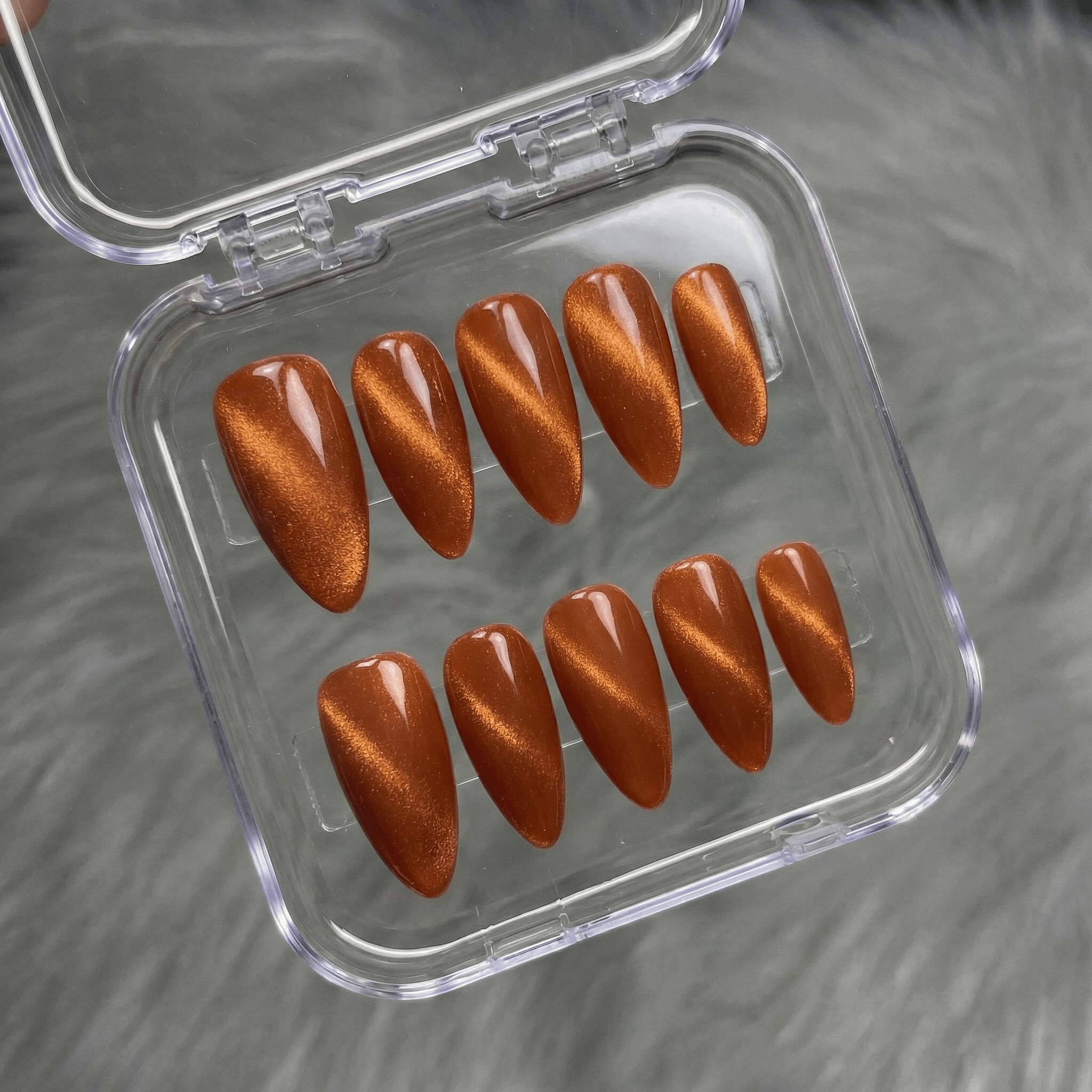 Crimson Aura press-on nails worn on hand – almond shape by Handora