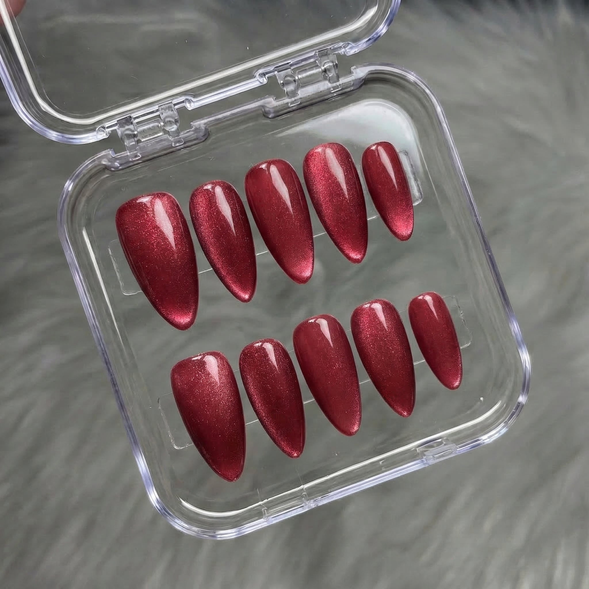 Crimson Aura press-on nails worn on hand – almond shape by Handora