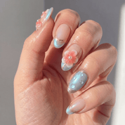 Floral Dewdrop press-on nails worn on hand – almond shape by Handora