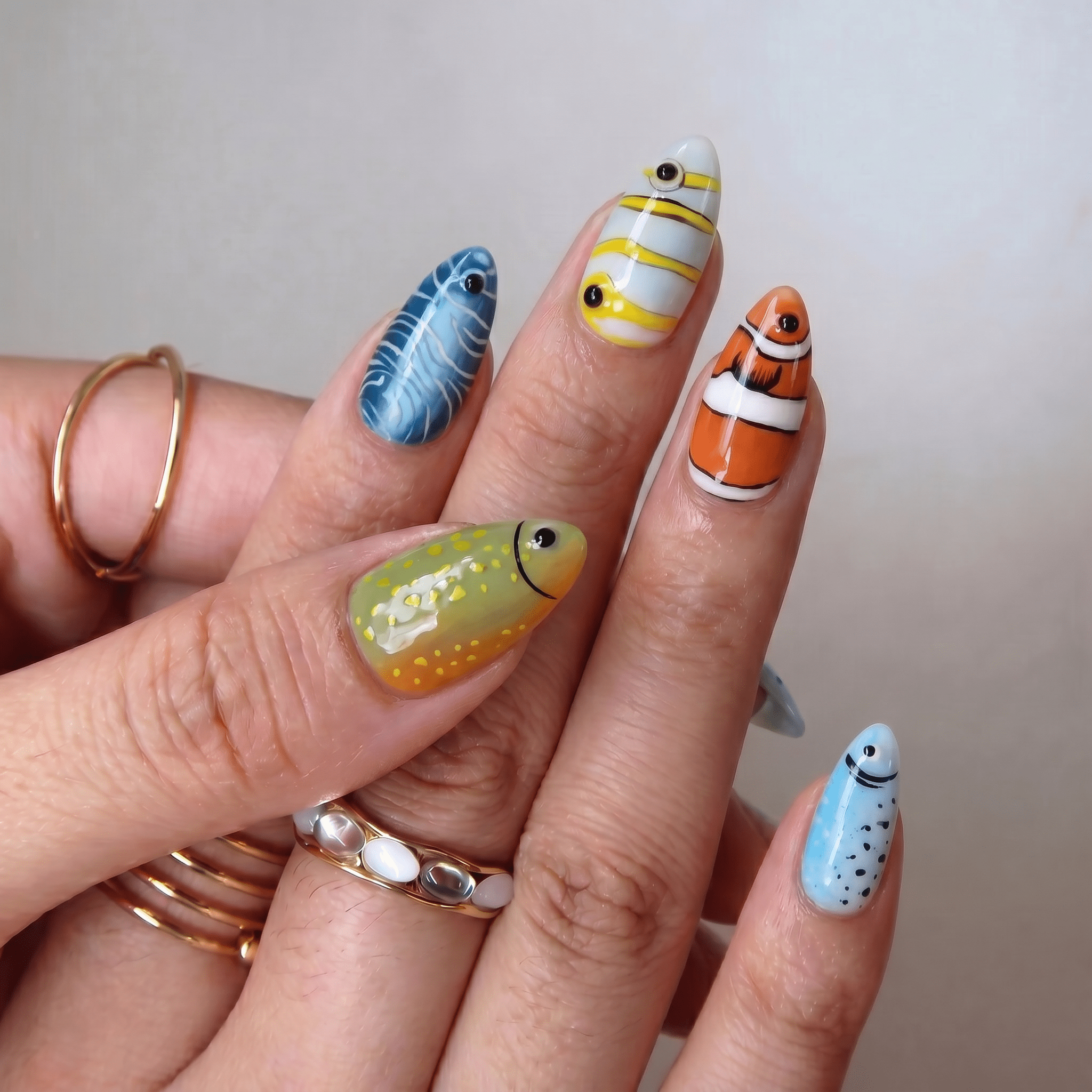 Ocean Fishes press-on nails worn on hand – almond shape by Handora