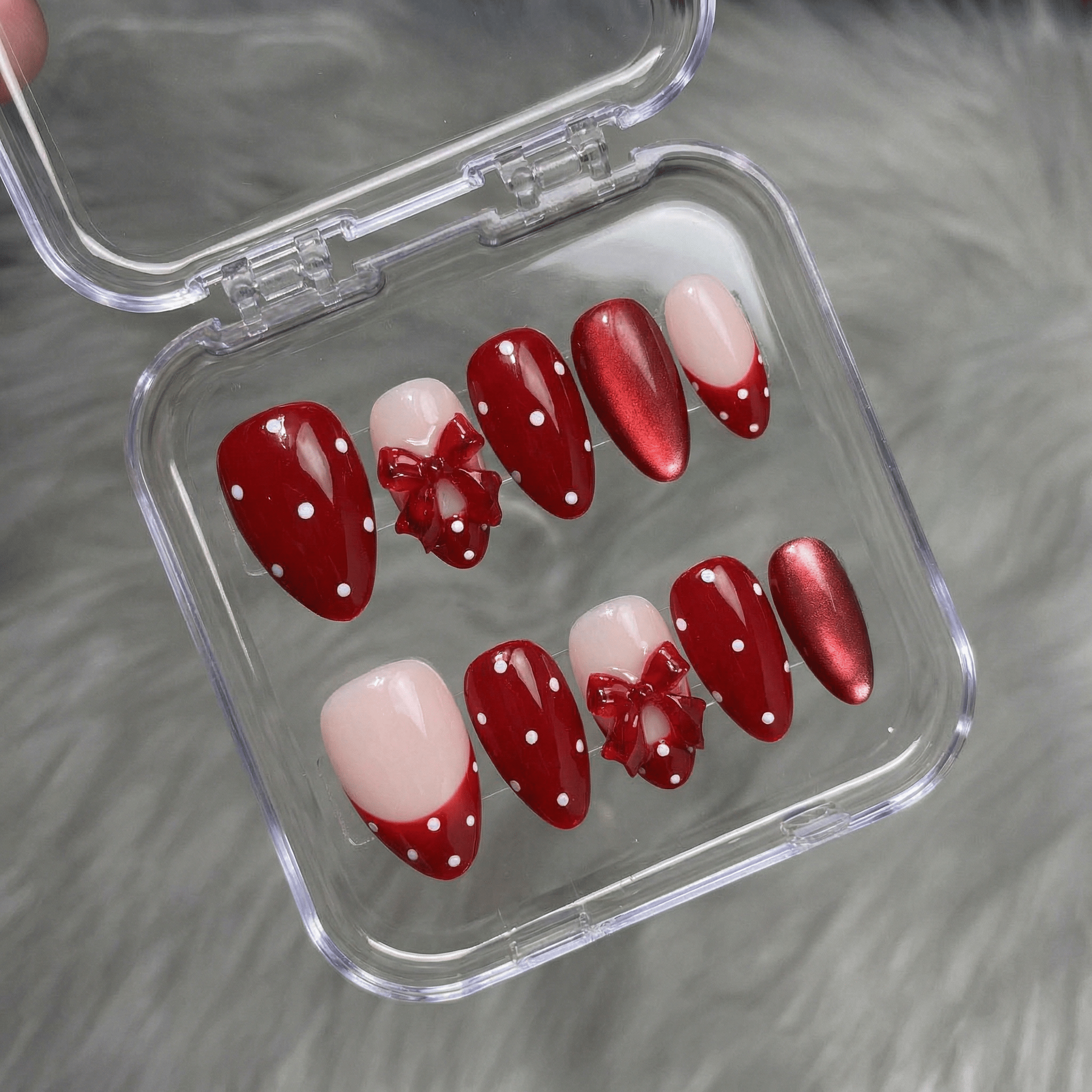 Ruby Polka press-on nails worn on hand – almond shape by Handora