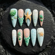 Seaside Treasures press-on nails worn on hand – almond shape by Handora