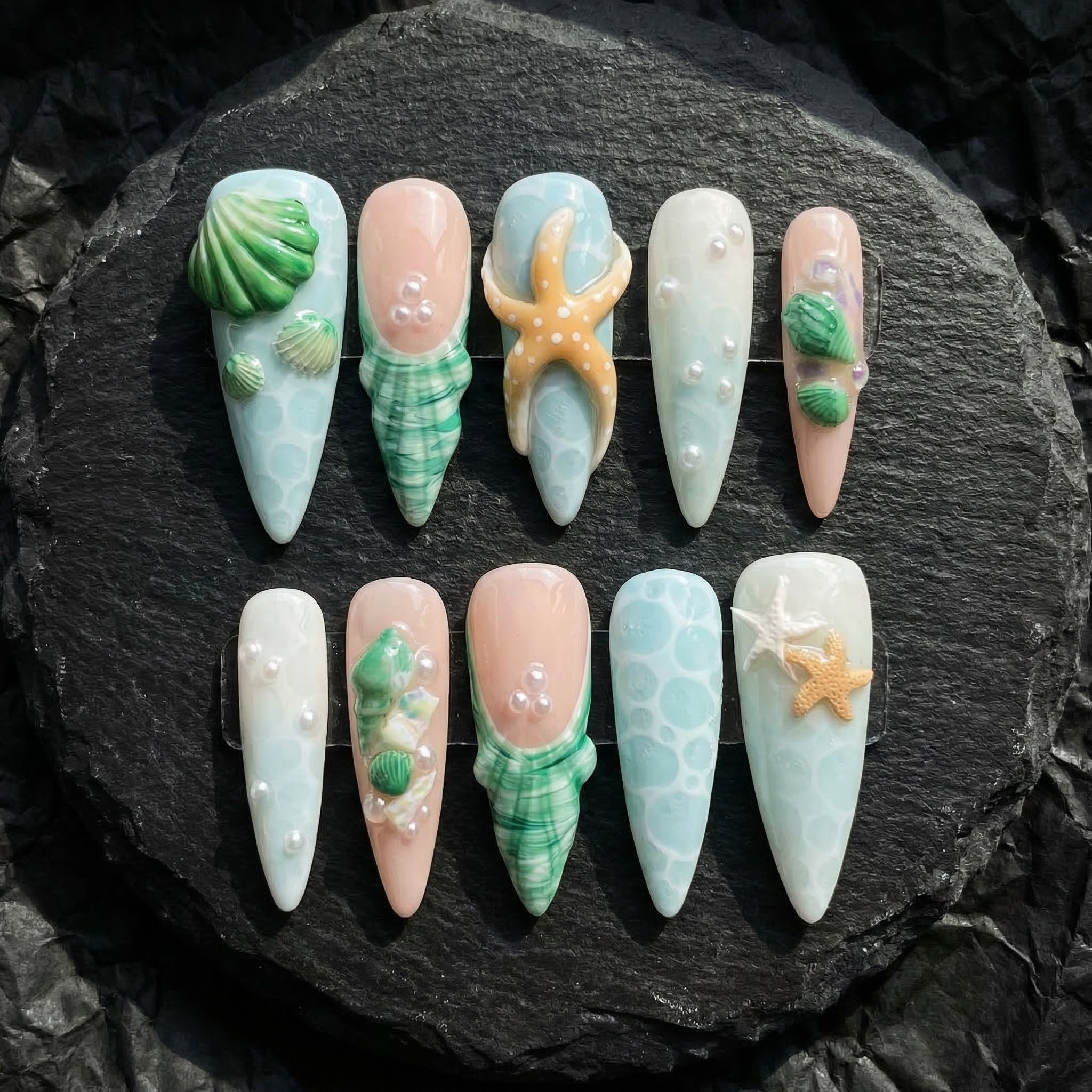 Seaside Treasures press-on nails worn on hand – almond shape by Handora