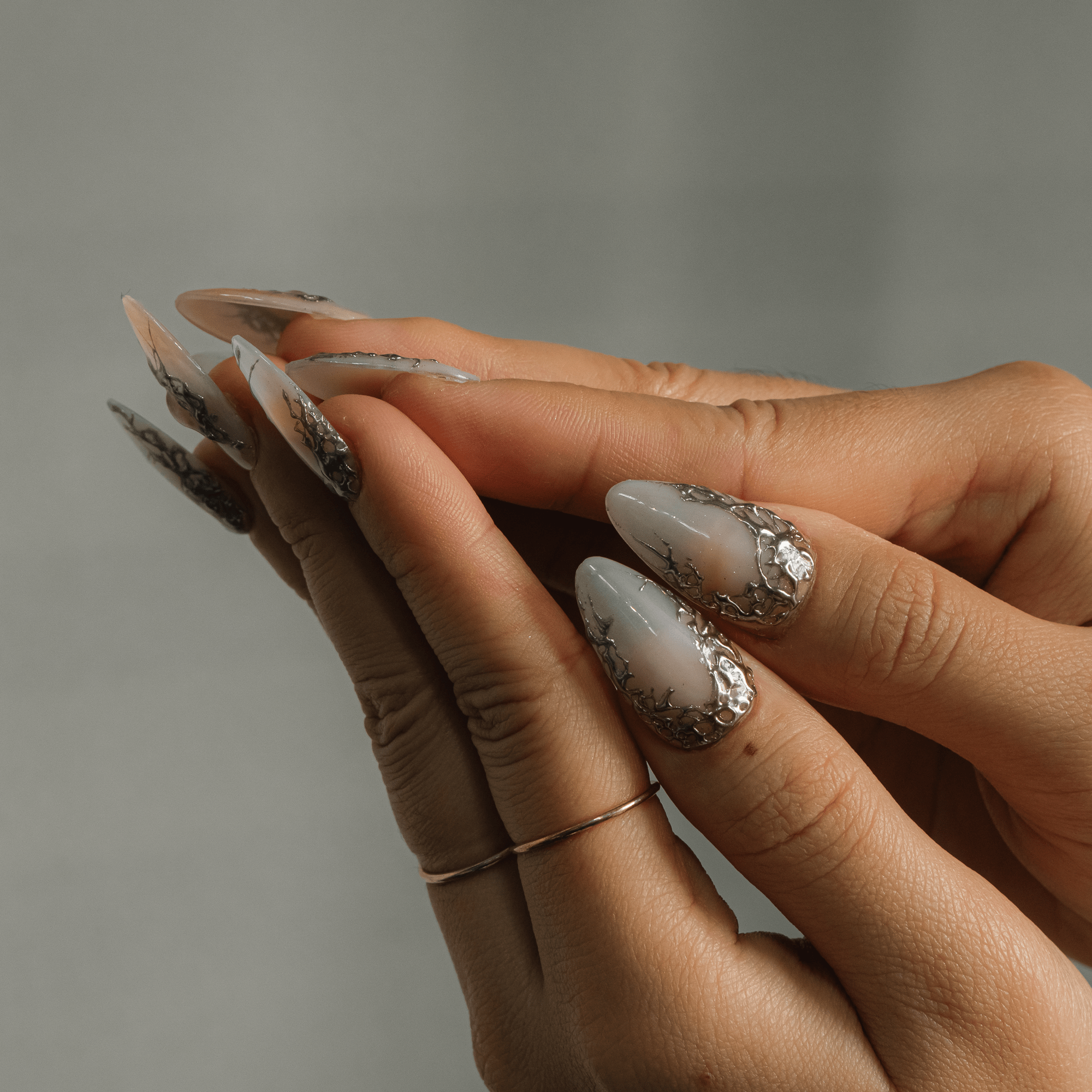 Silver Aura press-on nails worn on hand – almond shape by Handora