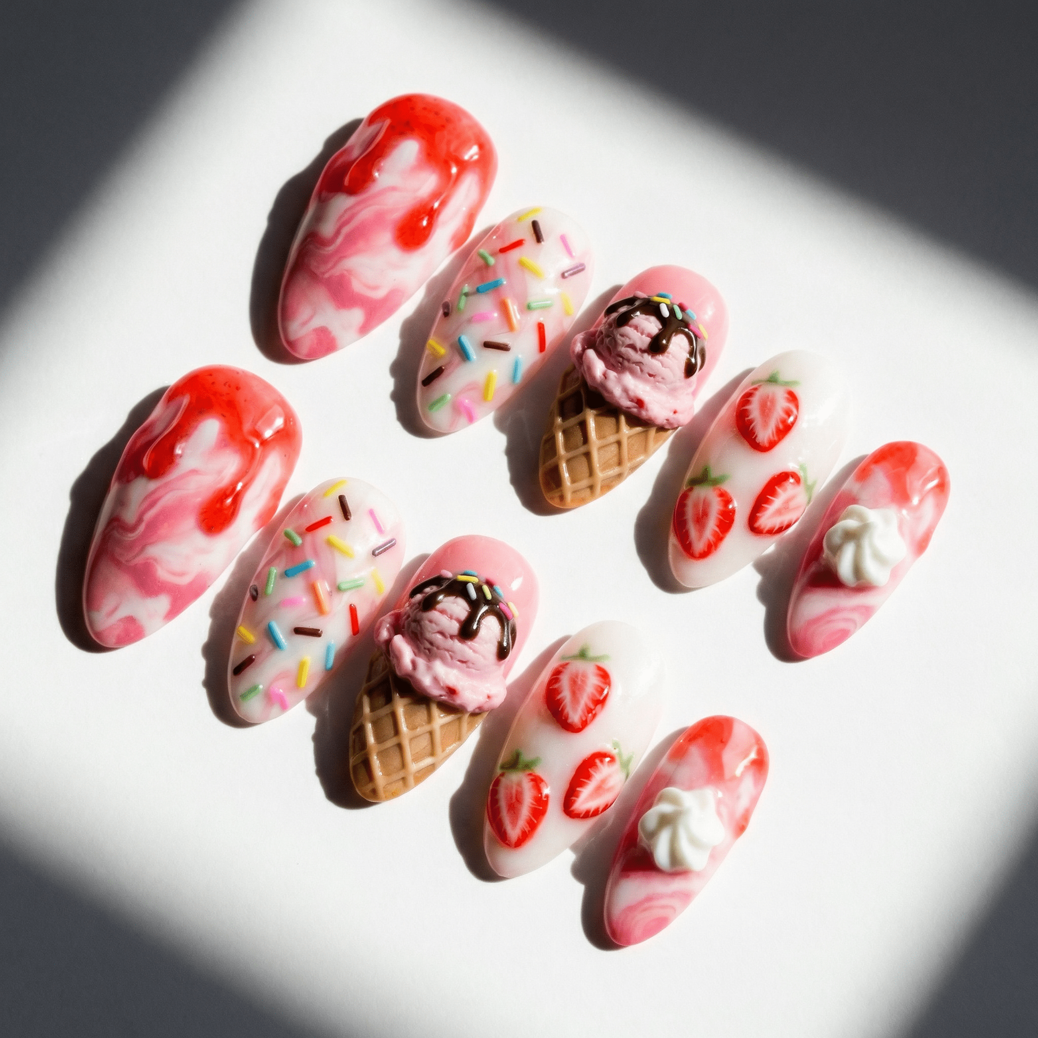 Strawberry Sundae press-on nails worn on hand – almond shape by Handora