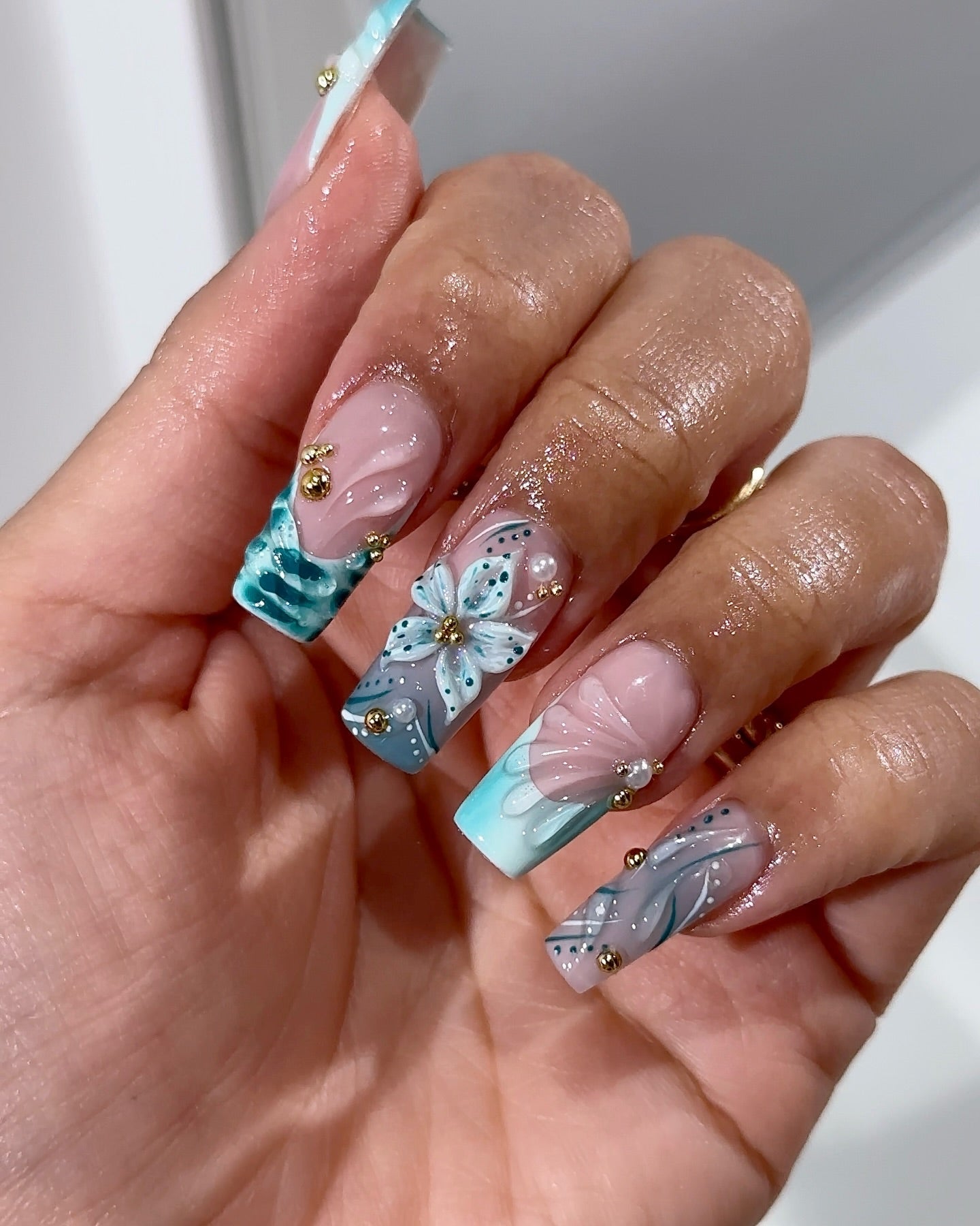 Teal Bloom press-on nails worn on hand – almond shape by Handora